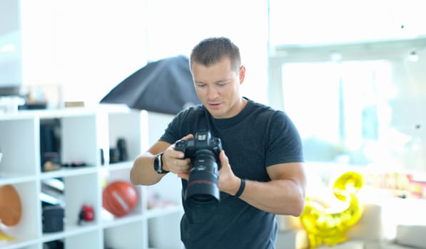 Male photographer holding black professional camera in his hands in studio. Hobbies doing what you love concept