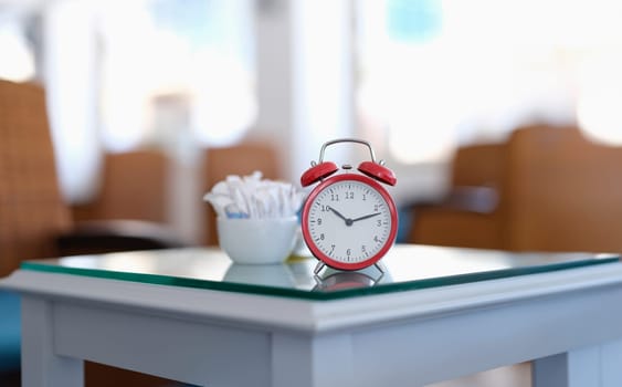 Red classic alarm clock standing on table in cafe closeup. Correct diet concept