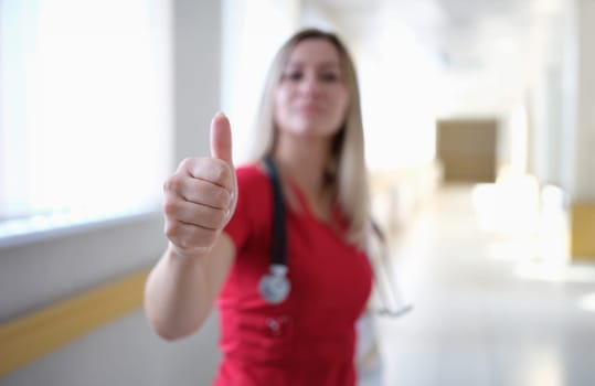 Woman doctor in red uniform showing thumb up closeup. Quality medical advice concept