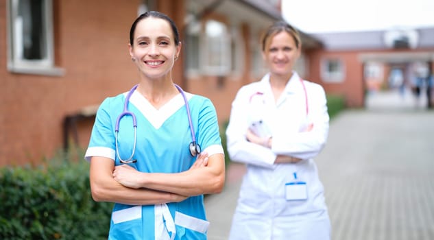 Female doctors in uniforms standing near clinic. Health insurance concept