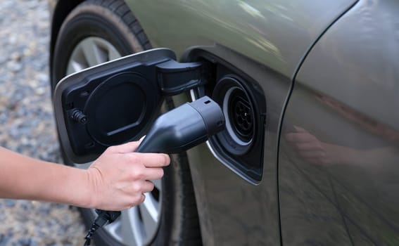 Man inserting electric cable into car charger closeup. Environmentally friendly cars concept