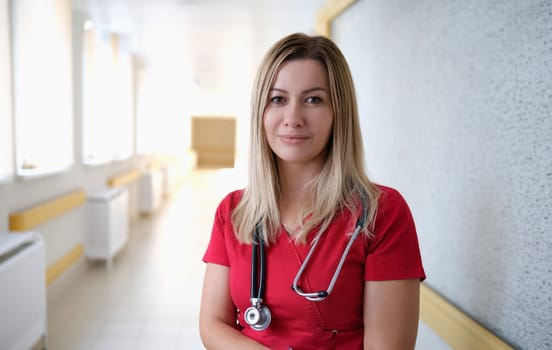 Portrait of young female doctor in red uniform in clinic. Health care concept