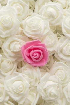 vertical image top view of background of white flowers and one pink flower. artificial flowers. Artificial white roses and one pink rose from foamiran. soft focus. flat lay