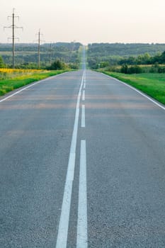 an asphalt road stretching to the horizon among the fields. photo