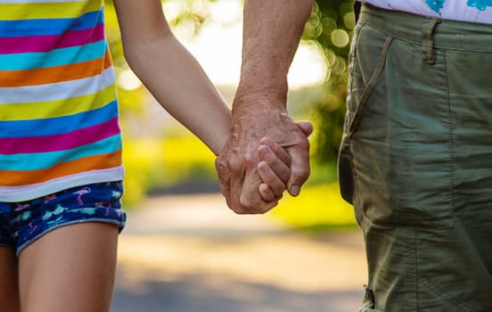 Child with grandmother holding hand. Selective focus. Nature.