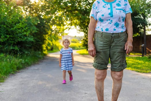 Child with grandmother holding hand. Selective focus. Nature.