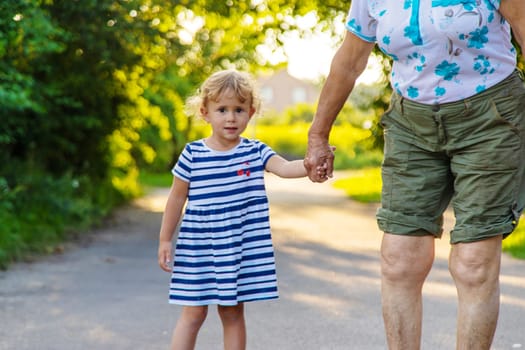 Child with grandmother holding hand. Selective focus. Nature.