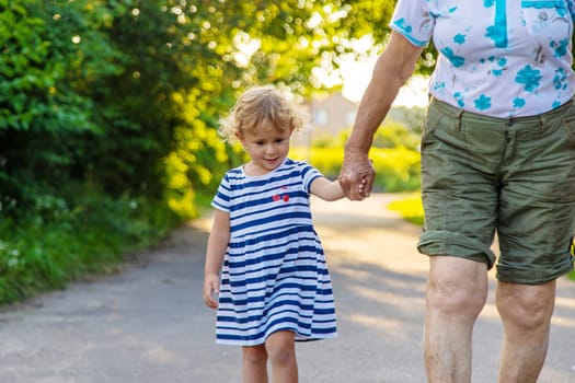 Child with grandmother holding hand. Selective focus. Nature.