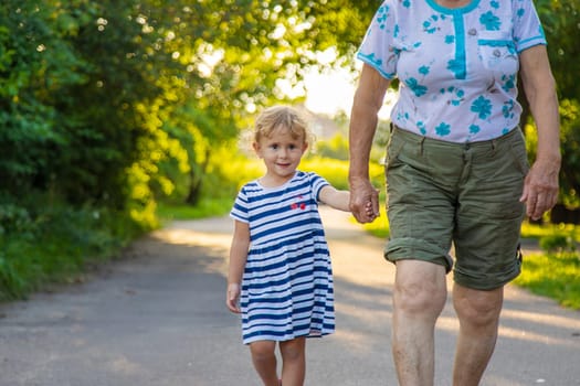 Child with grandmother holding hand. Selective focus. Nature.