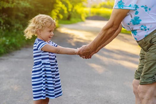 Child with grandmother holding hand. Selective focus. Nature.