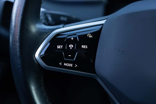 Close up of steering wheel of a new electric vehicle. Electric car control devices. Cruise control buttons, speed limitation, car's signal.