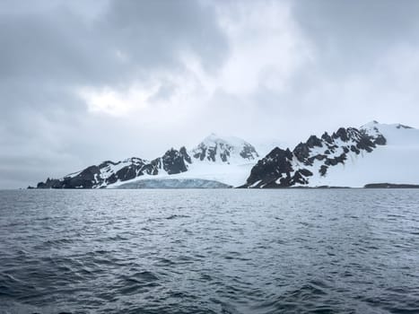 A huge high breakaway glacier in the southern ocean off the coast of Antarctica, the Antarctic Peninsula, the Southern Arctic Circle, azure water, cloudy weather. High quality photo