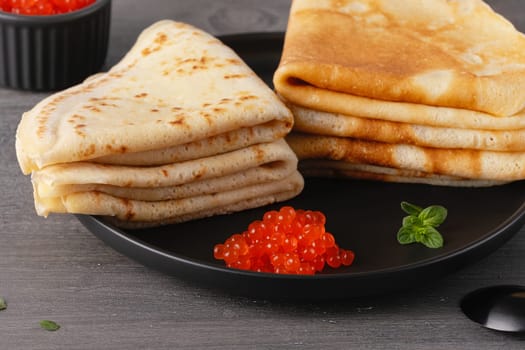 Pancakes with red caviar. Close-up of pancakes stacked on grey background.