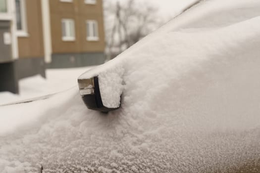 Heavy snowfall. Snow-covered car mirror in bad weather.