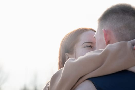 Outdoor photo of happy young woman enjoying date. cheerful romantic couple dating and hugging outdoors, closeup, sky background