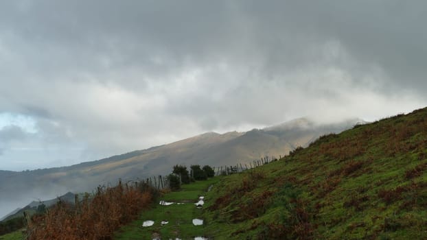 Trail with puddles of water on top of a mountain with cloudy skies