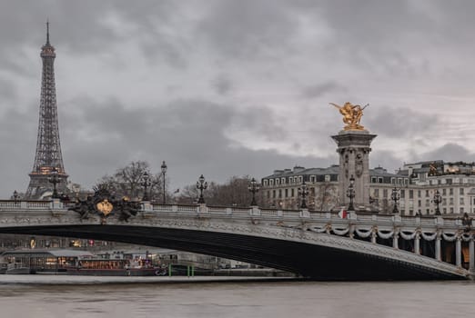 France, Paris - Jan 04, 2024 - Nice evening scenery of Eiffel Tower and Pont Alexandre III Bridge on Seine River in Paris. Destinations in Europe. Space for text, Selective focus.