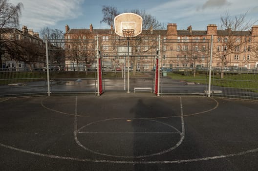 Edinburgh, Scotland, Jan 19, 2024 - Basketball backboard with the hoop metal ring at outdoor basketball courts in the park with old buildings background in the city downtown. Space for text, Selective focus.