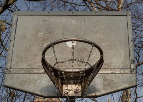 Edinburgh, Scotland, Jan 19, 2024 - Steel basketball backboard with the hoop metal ring and steel chain net seen from below. Street basketball court, Low angle view, Look up, Space for text, Selective focus.