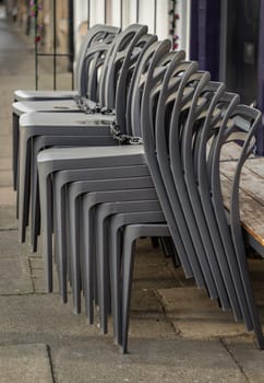 Pile of stacking silver gray plastic chairs are beside of The cafe terrace at sunny day. Detailed of pattern stack plastic chairs, Space for text, Selective focus.