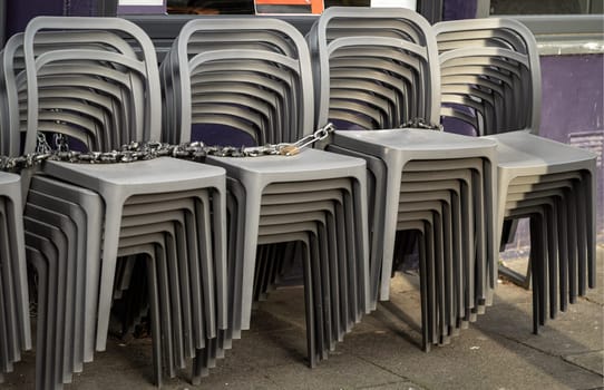 Pile of stacking silver gray plastic chairs are beside of The cafe terrace at sunny day. Detailed of pattern stack plastic chairs, Space for text, Selective focus.