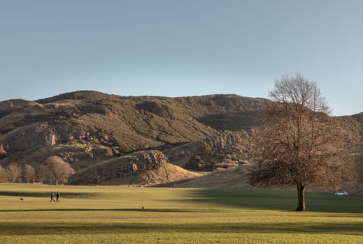 The breathtaking scenic landscape of Holyrood park with Salisbury Crags rugged hills and sky background. View of Edinburgh city. Space for text, Selective focus.