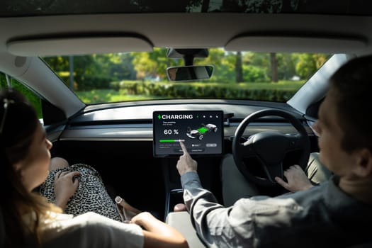 Electric car driver checks battery charging status, range and charging limit on app screen in the car. Smart technology device show EV car recharging data of electric storage in car battery innards.