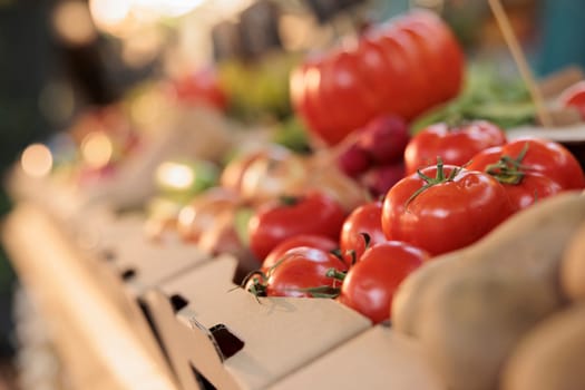 Natural ripe tomatoes in box on farmers market stand with various fruits and vegetables at farm store. Colorful homegrown local products, small business greenmarket for healthy nutrition. Close up.