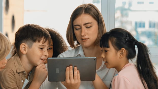 Smart teacher holding tablet while open online lesson to group of students. Skilled instructor explained engineering code lesson while young learner sitting and listening presentation. Erudition.