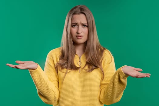 Confused pretty woman, shoulders up - can't help, makes gesture of I dont know. Difficult question, guilty reaction, puzzled stylish woman on blue background. High quality