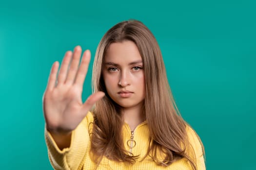 Uninterested lady disapproving with NO hand sign gesture. Denying, rejecting, disagree. Portrait of young woman on blue background, timeout concept. High quality