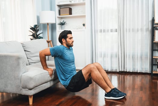 Athletic body and active sporty man using furniture for effective targeting muscle gain exercise at gaiety home exercise as concept of healthy fit body home workout lifestyle.