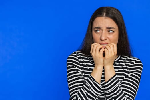 Scared stressed woman terrified about danger problems, suffering phobia anxiety disorder expresses fear waving no insecure stress panic. Depressed fearful girl on blue studio background. Copy-space