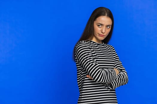 Offended sad nervous Caucasian woman having misunderstanding, frustrated after quarrel, fail, lose, ignores and does not want to communicate, talk. Girl isolated on blue background. Copy-space