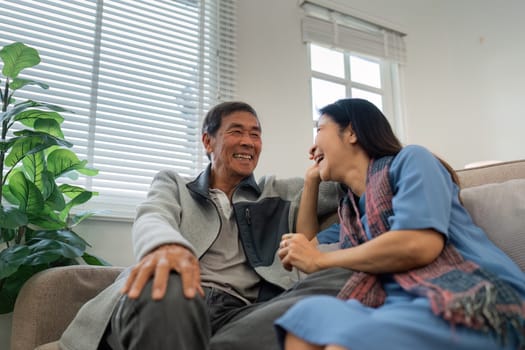 Older couples sit and chat and head over each other relaxed and happy on sofa at home on weekday in comfortable.