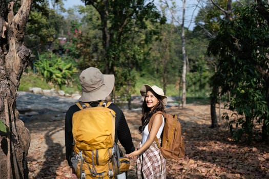 Happy LGBT Lesbian couple Travelers Hiking with Backpacks in forest Trail. LGBT Lesbian Couple Hikers with backpacks walks in mountains in vacation.