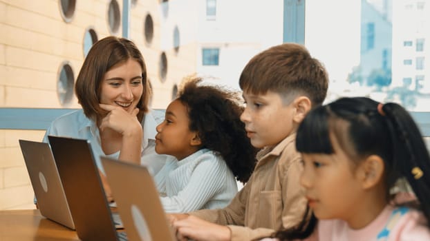 Smart teacher teaching and looking student using laptop at classroom. Professional instructor explained about programing engineering code or prompt while studying and learning program. Erudition.