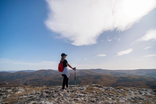 woman backpack on mountain peak looking in beautiful mountain valley in autumn. Landscape with sporty young woman, blu sky in fall. Hiking. Nature.