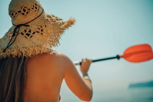 Woman in kayak back view. Happy woman with long hair in a swimsuit and hat floating in kayak on the sea. Summer holiday vacation. Summer holidays vacation at sea