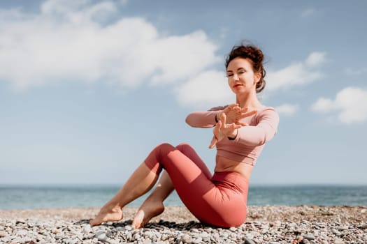 Young woman with long hair in white swimsuit and boho style braclets practicing outdoors on yoga mat by the sea on a sunset. Women's yoga fitness routine. Healthy lifestyle, harmony and meditation