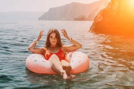 Woman summer sea. Happy woman swimming with inflatable donut on the beach in summer sunny day, surrounded by volcanic mountains. Summer vacation concept