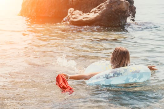 Woman summer sea. Happy woman swimming with inflatable donut on the beach in summer sunny day, surrounded by volcanic mountains. Summer vacation concept