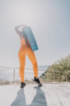 Fitness woman sea. Outdoor workout on yoga mat in park near to ocean beach. Female fitness pilates yoga routine concept. Healthy lifestyle. Happy fit woman exercising with rubber band in park.