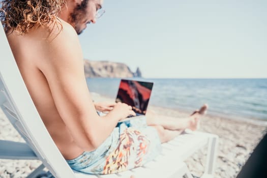 Digital nomad, Business man working on laptop by the sea. Man typing on computer by the sea at sunset, makes a business transaction online from a distance. Freelance, remote work on vacation