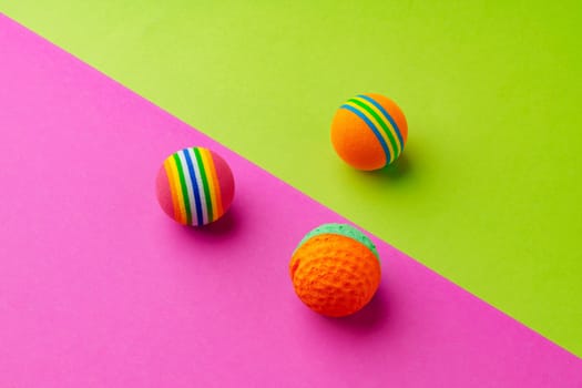 Pet toys balls on pink and green background studio shot top view