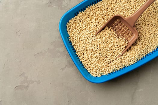 Pet litter tray with wooden filler on gray background close up