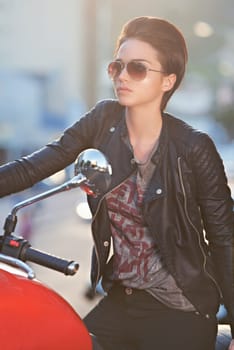 Motorcycle, leather and biker in city with sunglasses for travel, transport or road trip as rebel. Fashion, street and woman with attitude on classic or vintage bike for transportation or journey.