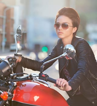 Motorcycle, power and woman in city with sunglasses for travel, transport or road trip as rebel. Fashion, street and model in leather jacket on classic or vintage bike for transportation or journey.
