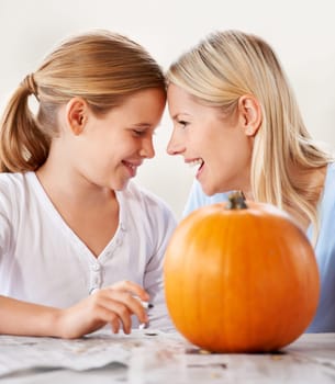 Mother, daughter or happy with pumpkin for halloween, celebration or decoration in kitchen of apartment home. Family, face or smile and vegetable for preparation, holiday or creative event in house.