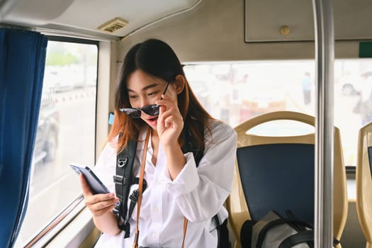 Surprised young woman reading message on her mobile phone while commuting by bus.